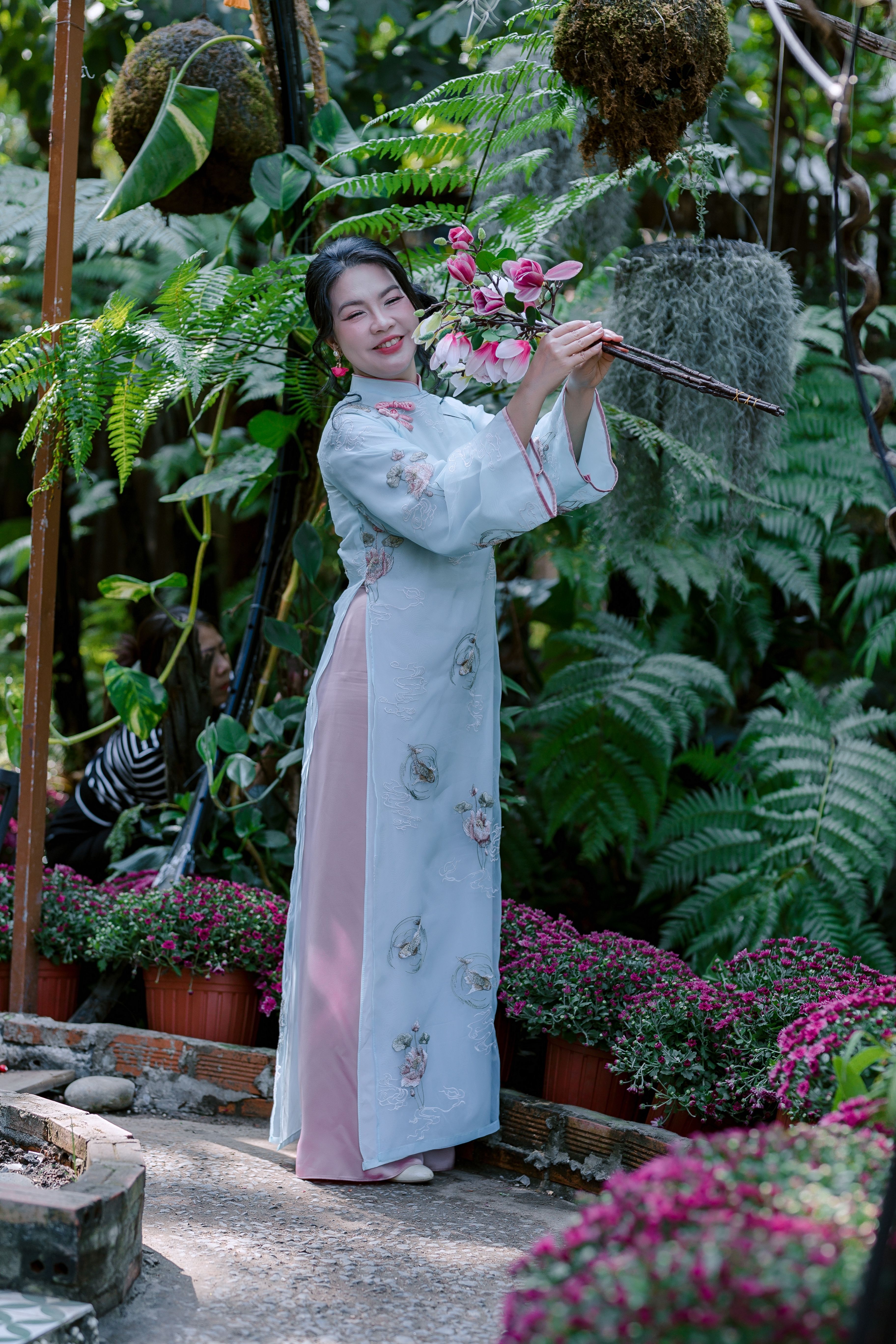 Woman in Traditional Dress Holding Flowers in Garden · Free Stock Photo