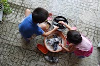 Children Washing Shoes Outdoors in Thuận An