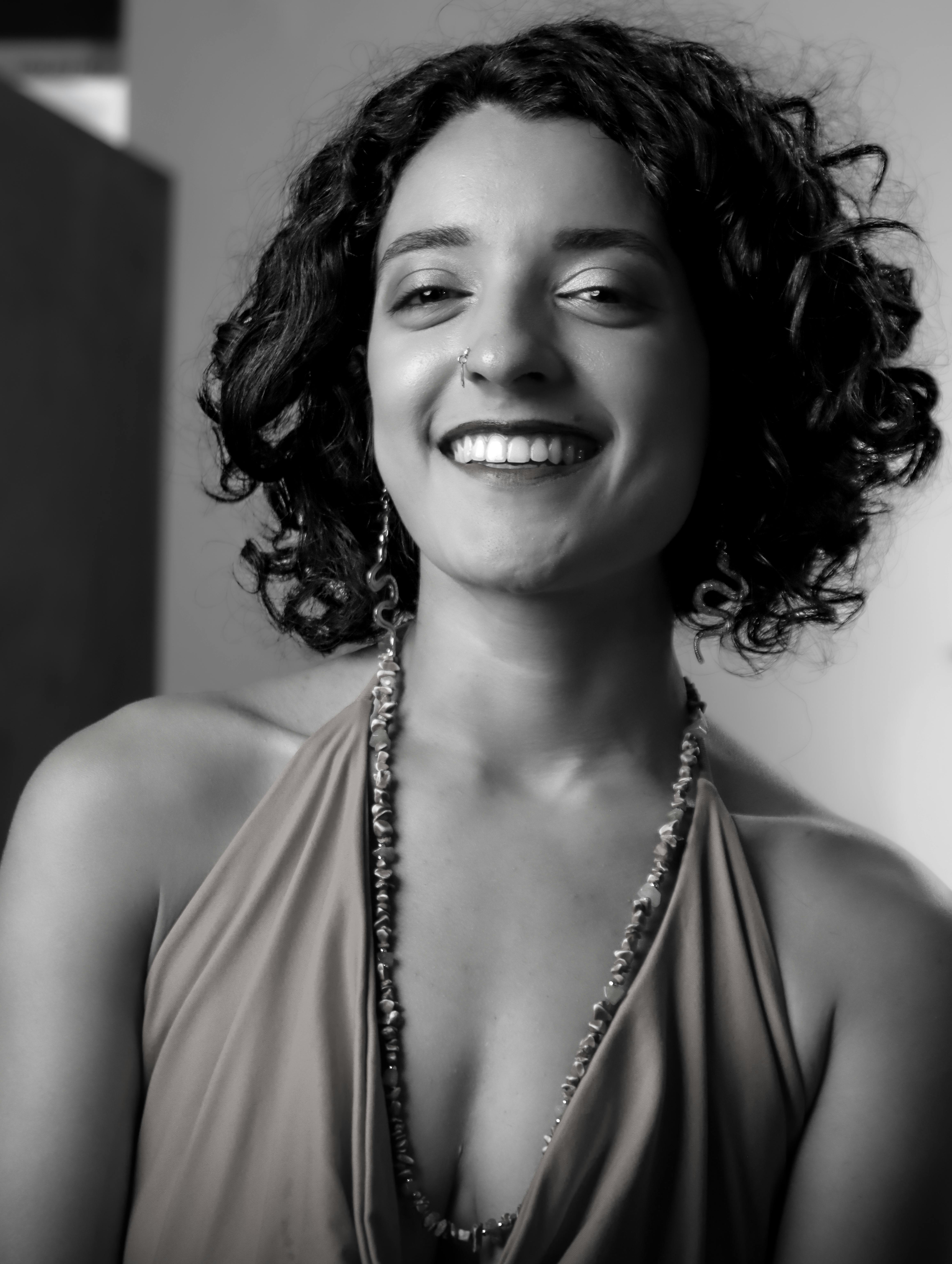 Captivating black and white portrait of a smiling woman with curly hair, exuding elegance.