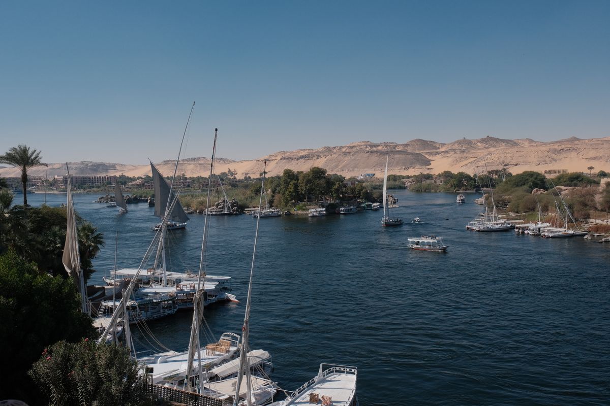 Sailboats moored on the Nile with desert hills and palm trees visible along the riverbank