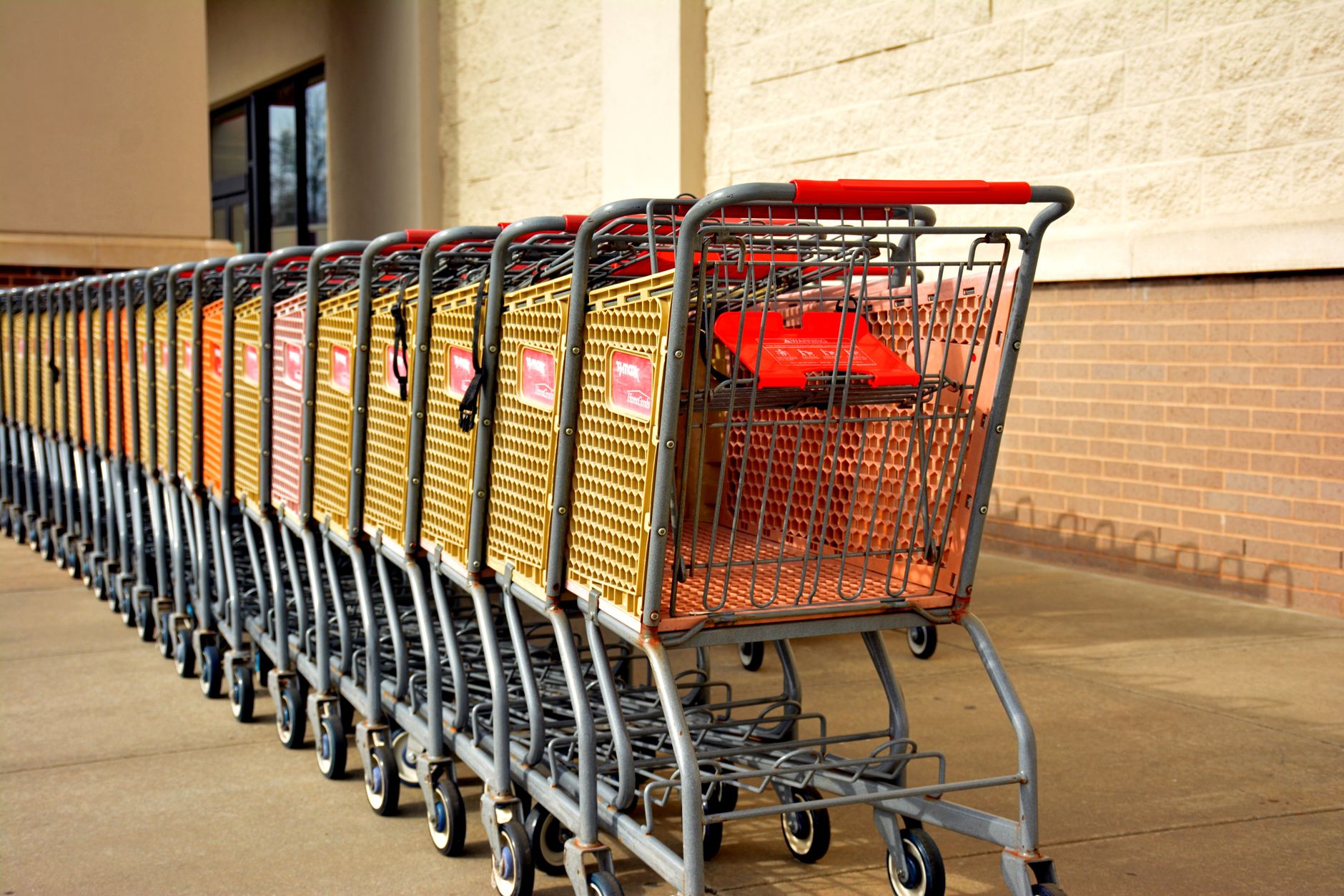 Bright row of stacked shopping carts lined up in front of a retail store on a sunny day.