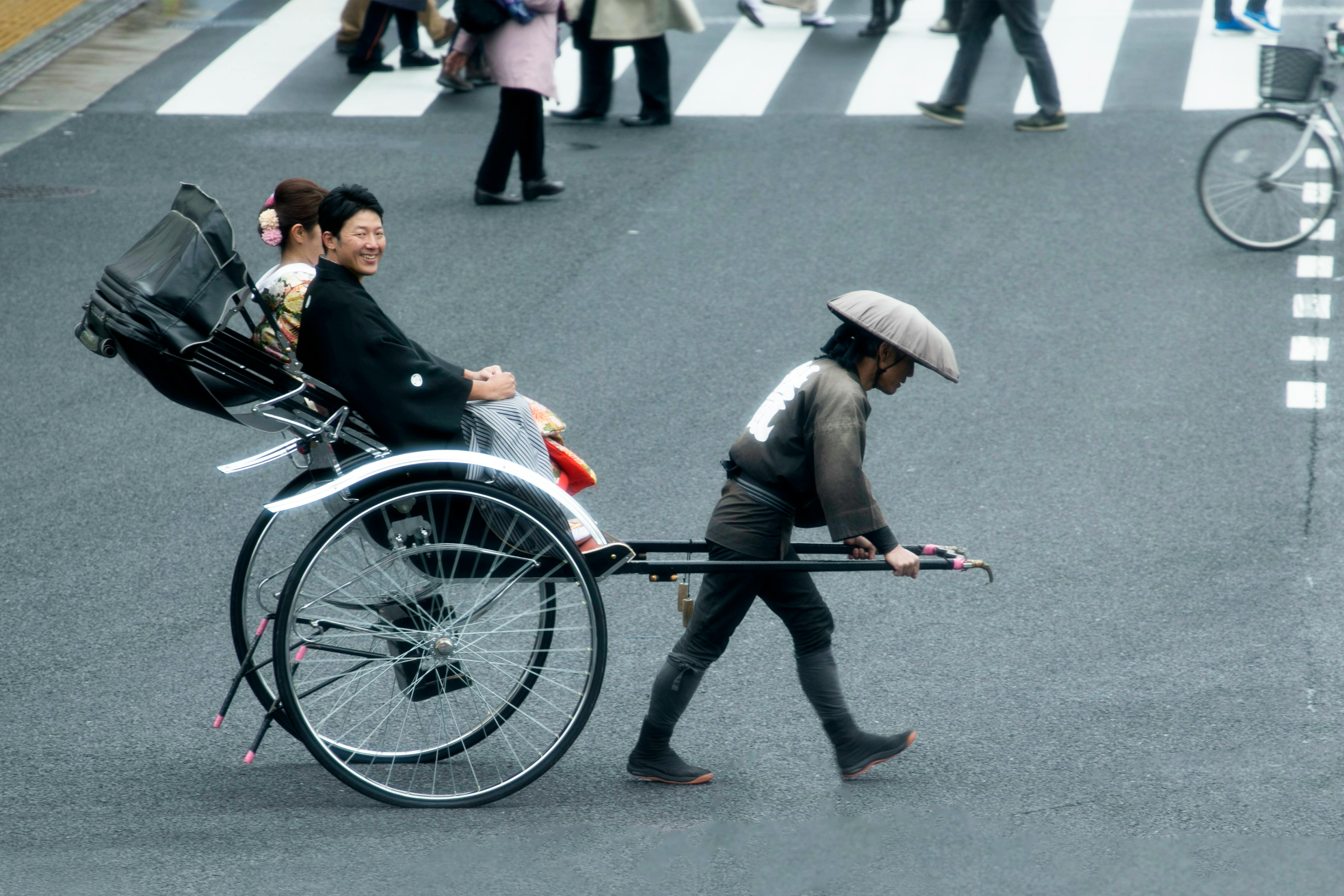 Free A traditional Japanese rickshaw ride through a crosswalk, capturing cultural and urban life. Stock Photo