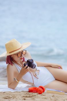 Fashionable woman with camera on a sandy beach on a summer day.