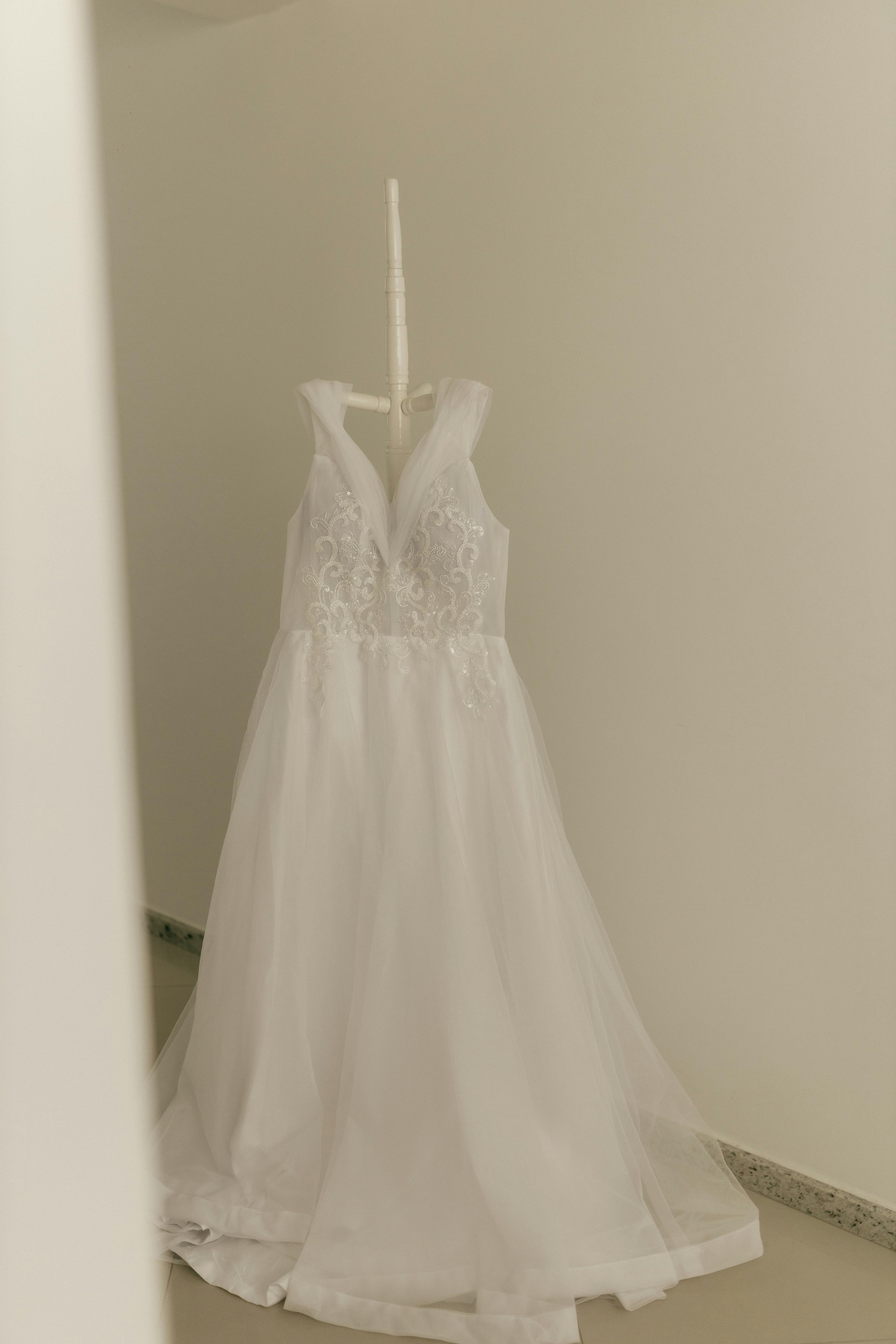 Beautiful white wedding dress with delicate lace patterns hanging elegantly in a minimal space.