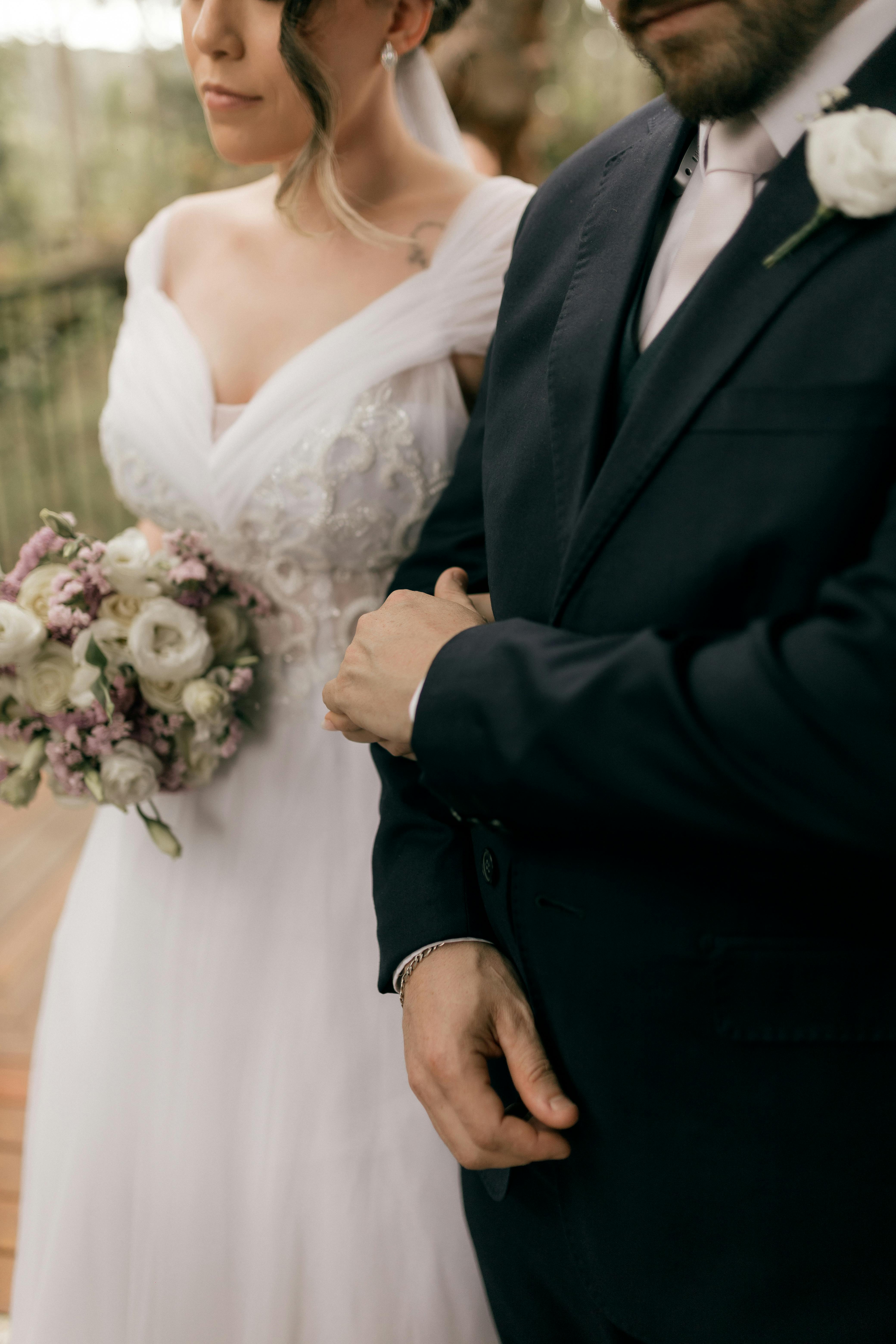 Gratuit Un couple de jeunes mariés élégants s'enlaçant, un magnifique bouquet de fleurs symbolisant l'amour et l'union. Photos
