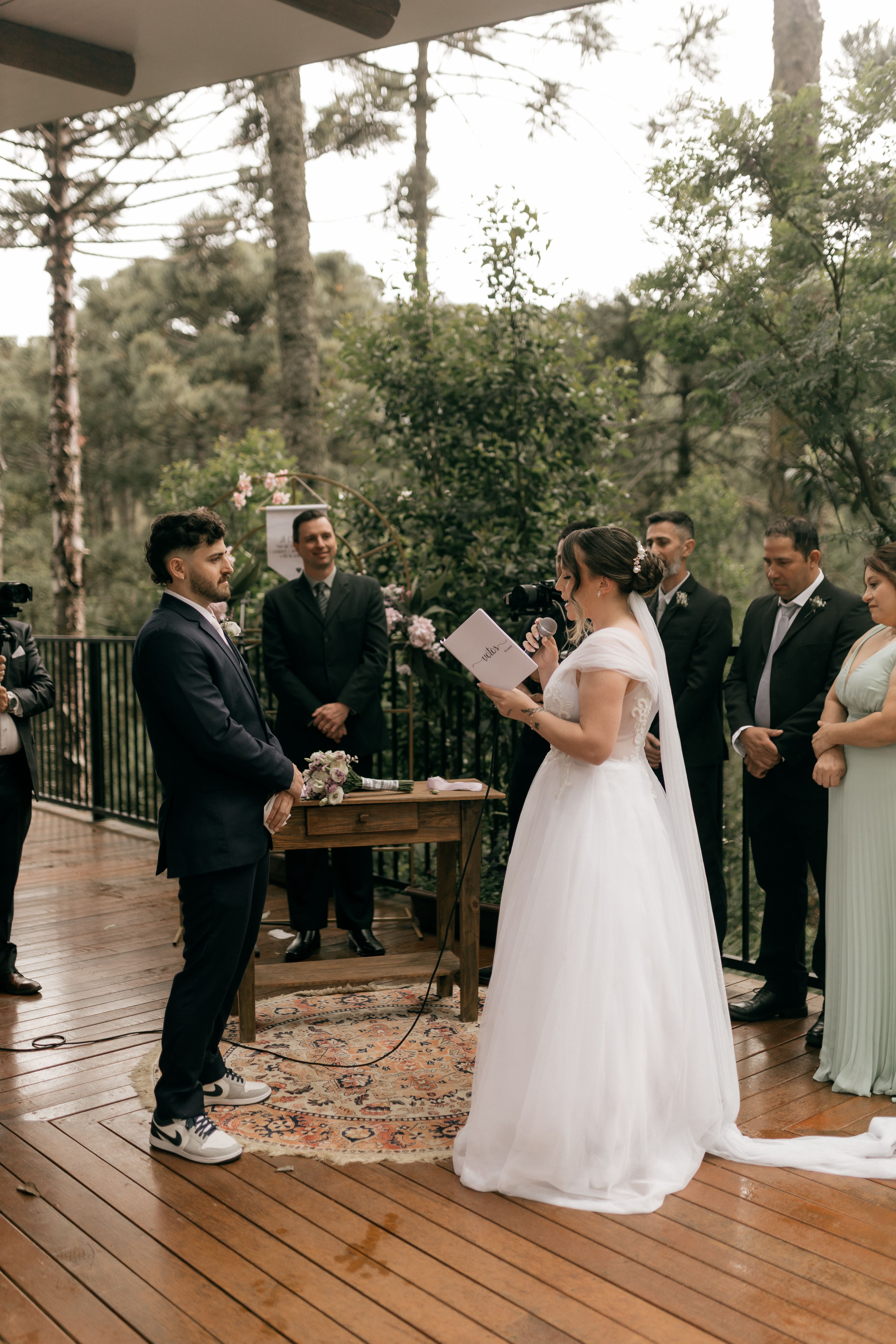 Couple exchanging vows at an enchanting outdoor wedding ceremony on a wooden deck.