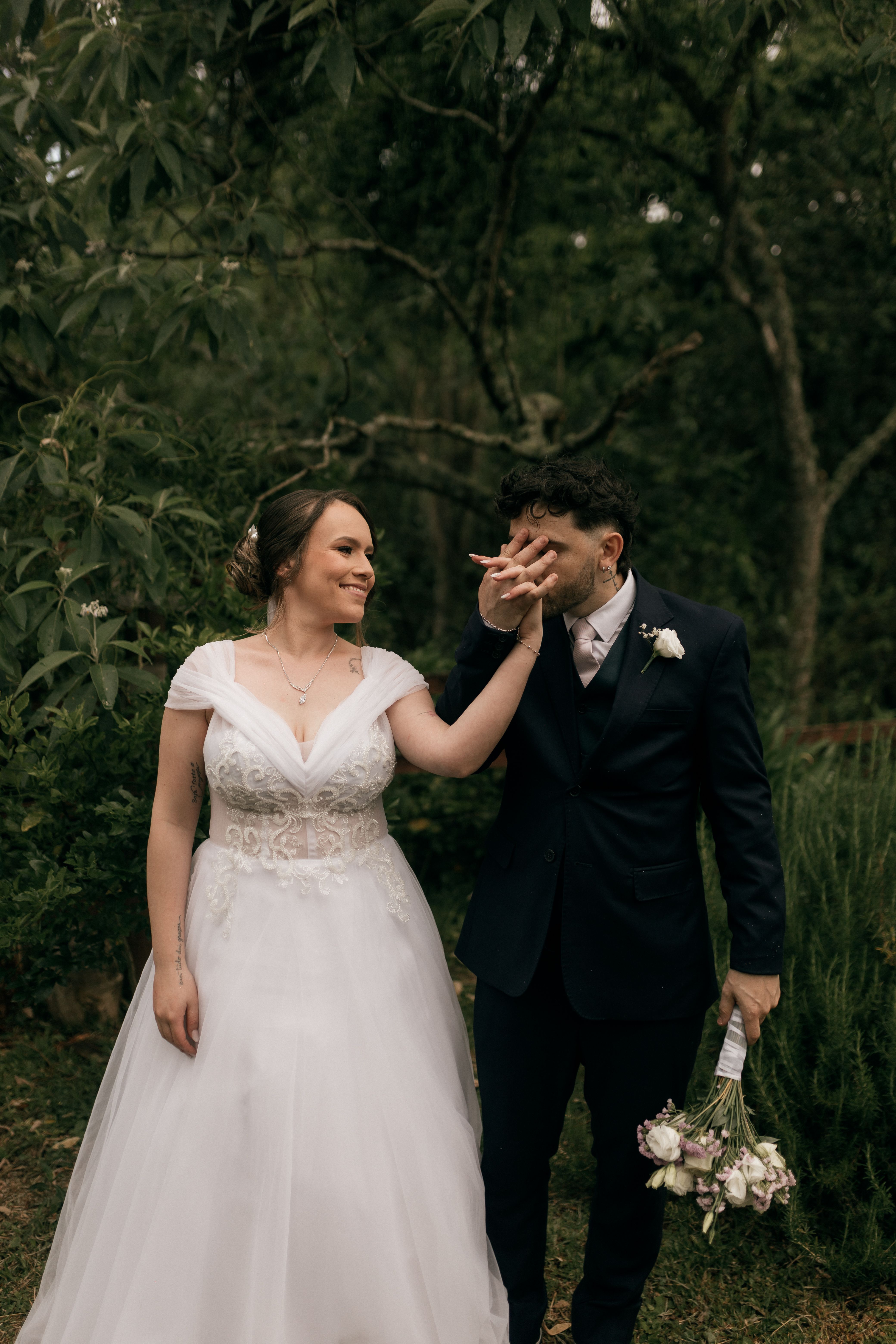 Bride and groom share a romantic moment outdoors in a lush setting.
