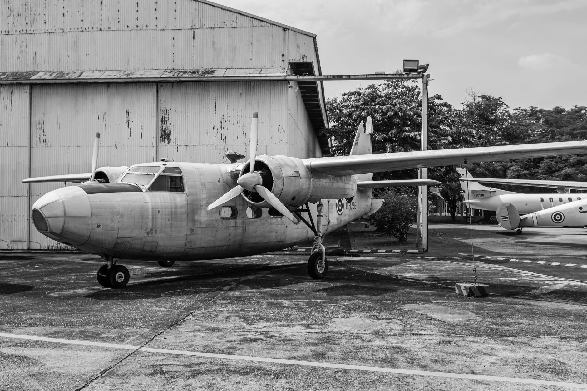 Black and white image of a vintage military aircraft parked outdoors.