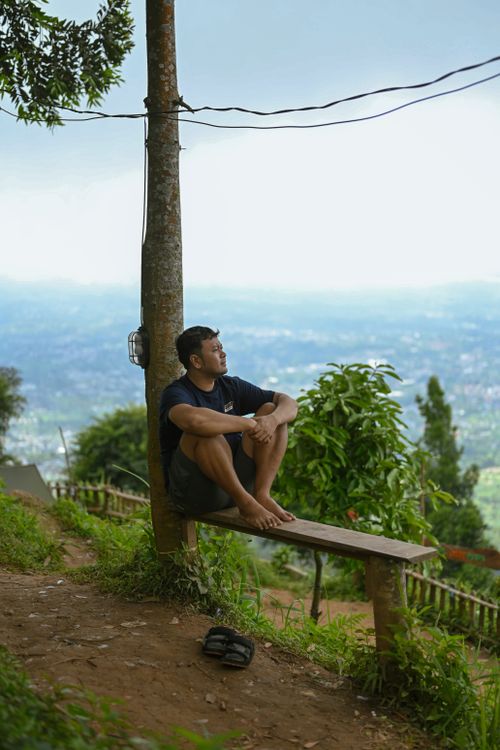 Free Man sitting on a bench, enjoying the view amidst nature in Indonesia. Stock Photo