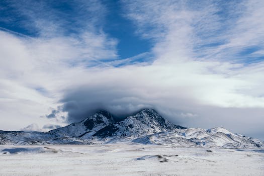 Majestic snow-covered mountains beneath a dramatic cloudy sky in a winter landscape.