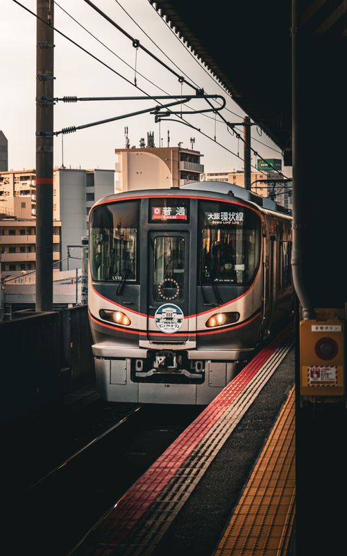 Free A sleek train arrives at an urban station in Osaka, Japan during sunset. Stock Photo