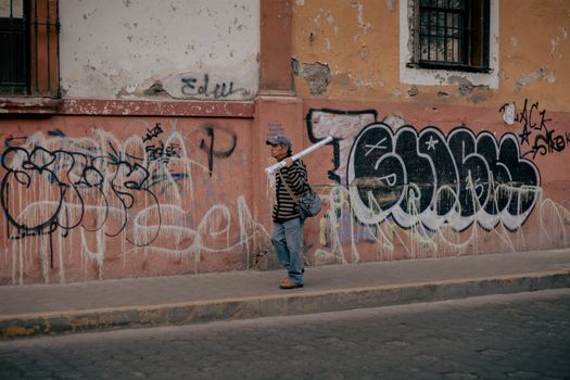 Urban street scene featuring a man walking past graffiti on a wall in Pachuca, Mexico.