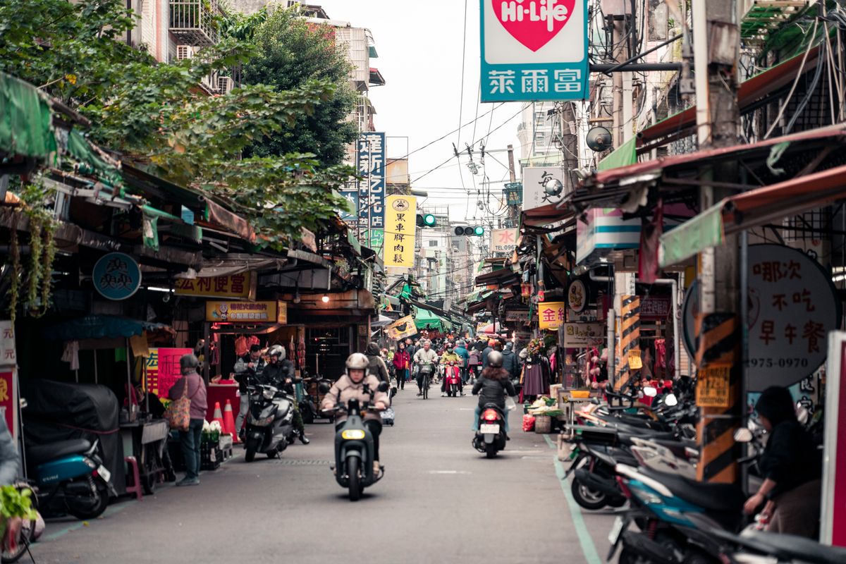 Bustling street market in Taipei, Taiwan, with scooters and neon signs at night