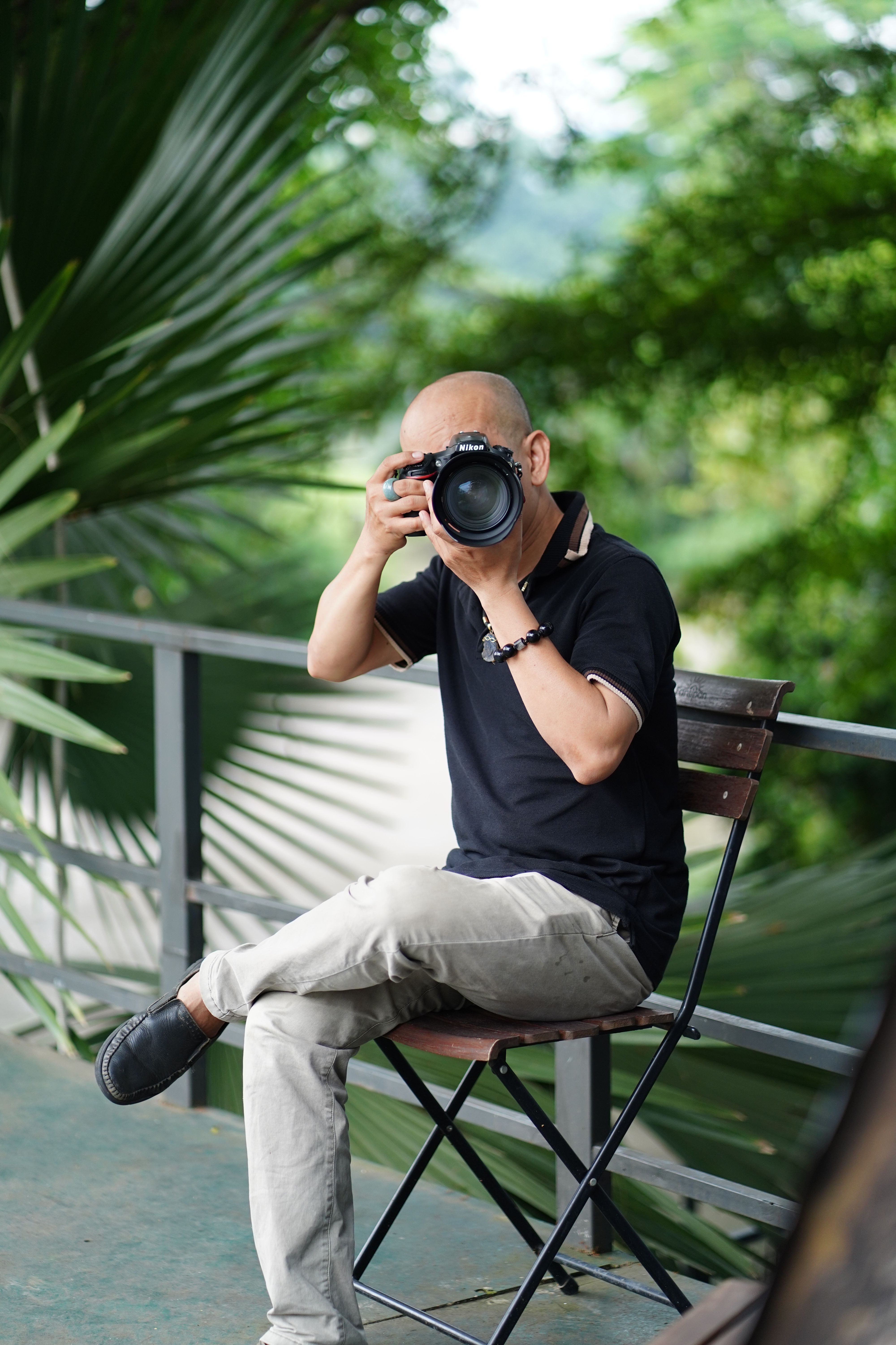 A skilled photographer sitting outdoors capturing nature with a DSLR camera.