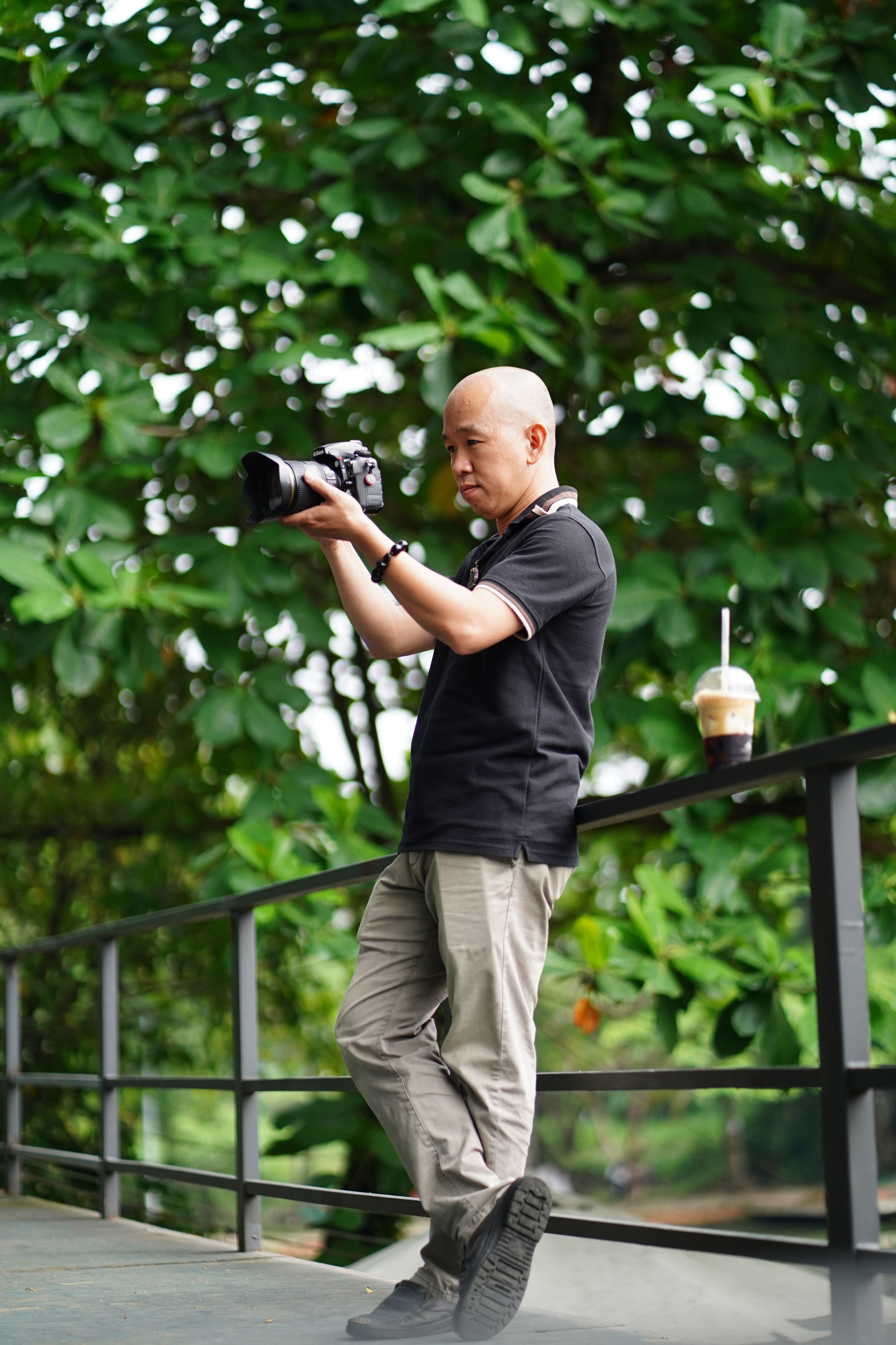 A photographer in a lush green outdoor setting taking pictures with a camera.