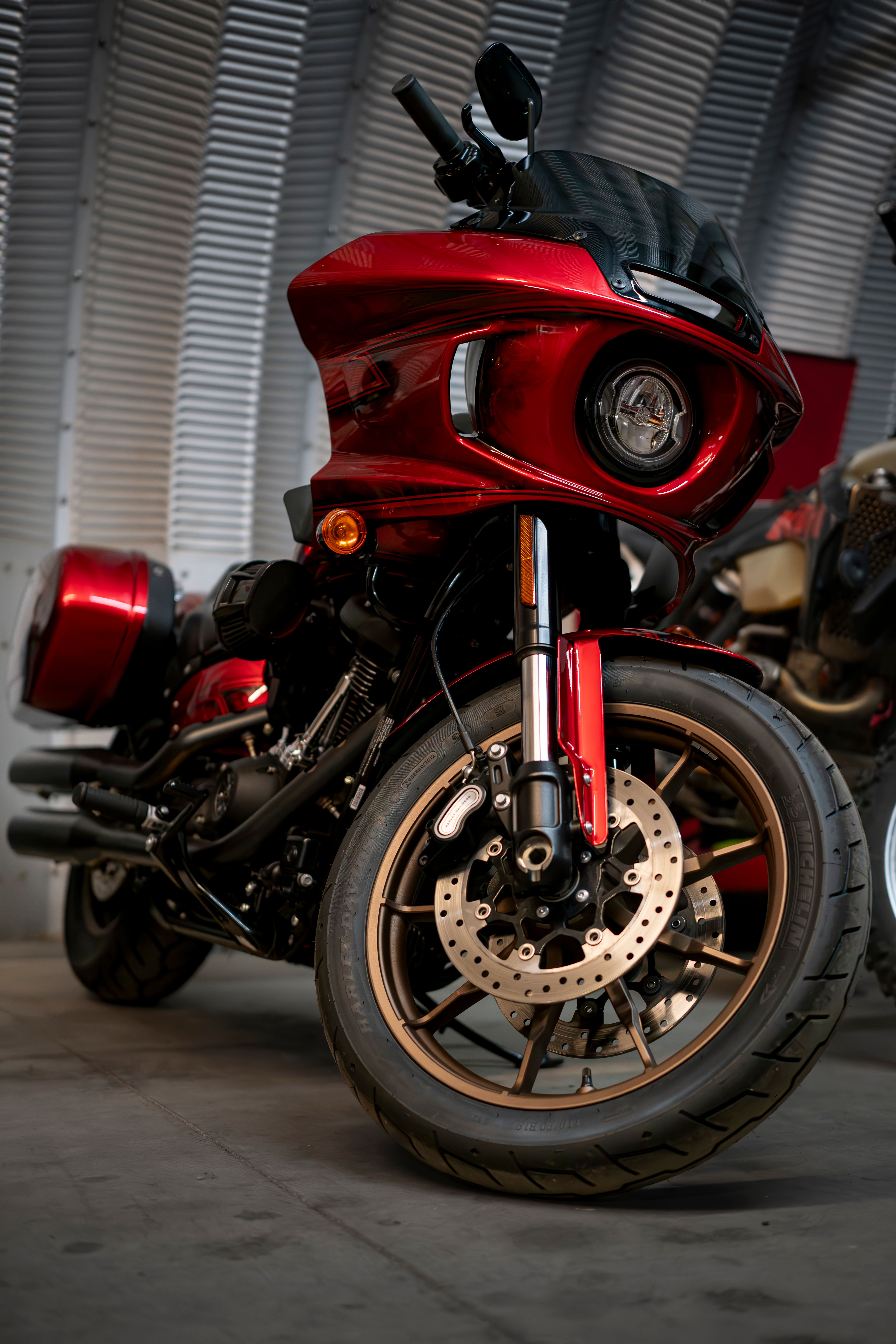 A modern red custom motorcycle parked indoors with detailed design and shiny metallic finish.