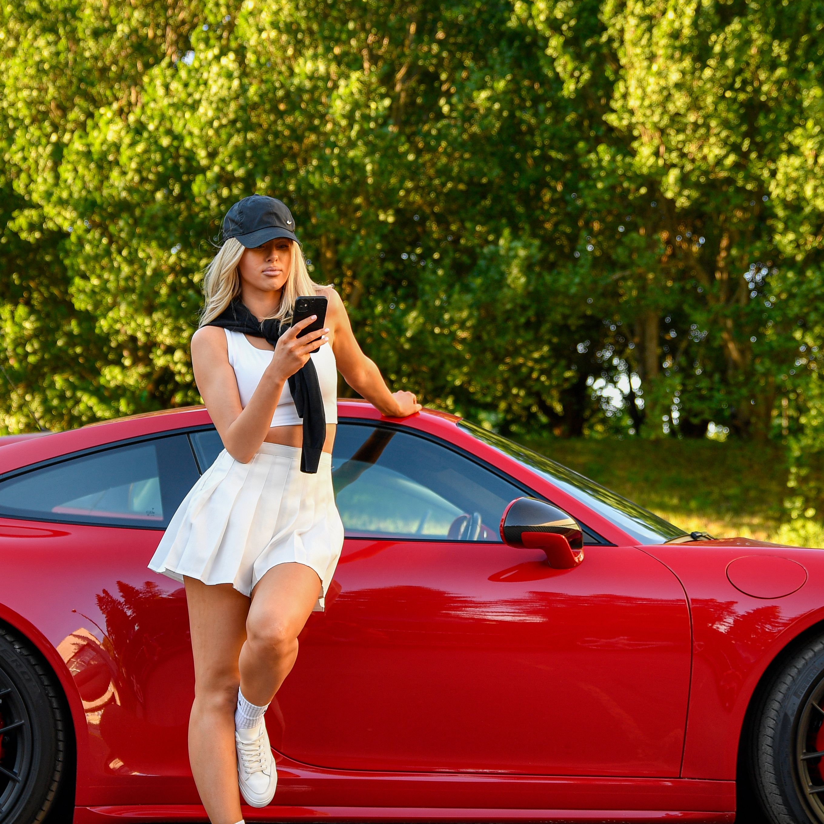 Blonde woman posing with a red luxury sports car outdoors in Tallinn, Estonia.