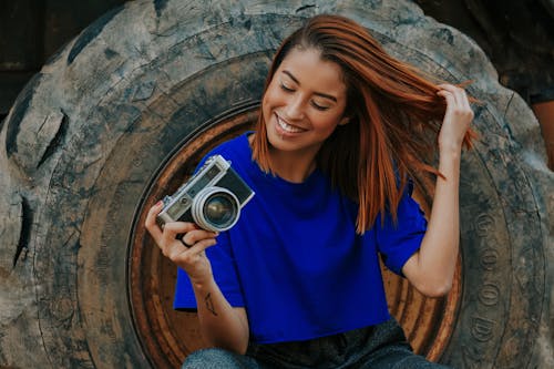 Foto Fokus Dangkal Wanita Dengan Kamera Memegang Kaos Biru