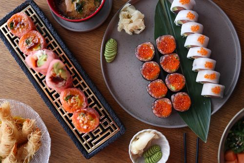 Free Top-down view of an assorted sushi platter with wasabi, ginger, and dipping sauces on a wooden table. Stock Photo