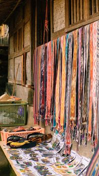 Vibrant traditional woven textiles hanging outdoors beside a rustic wooden wall. - Fotografer Sidoarjo