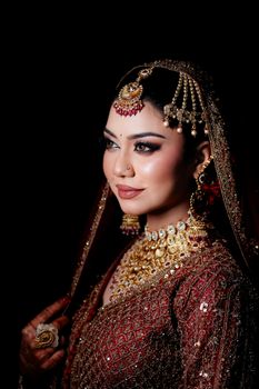 Stunning portrait of a South Asian bride in traditional red attire and jewelry.