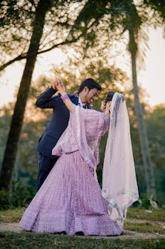 A romantic couple dance in traditional attire in a serene outdoor setting.