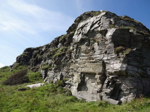 Free Explore the rugged beauty of a rocky cliff in Cornwall, highlighted by lush greenery and blue skies. Stock Photo