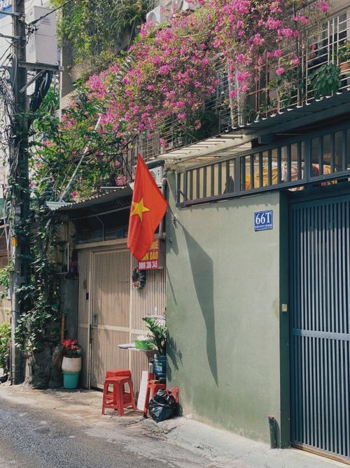 Free A vibrant Vietnamese street featuring a flag, blooming flowers, and charming architecture. Stock Photo