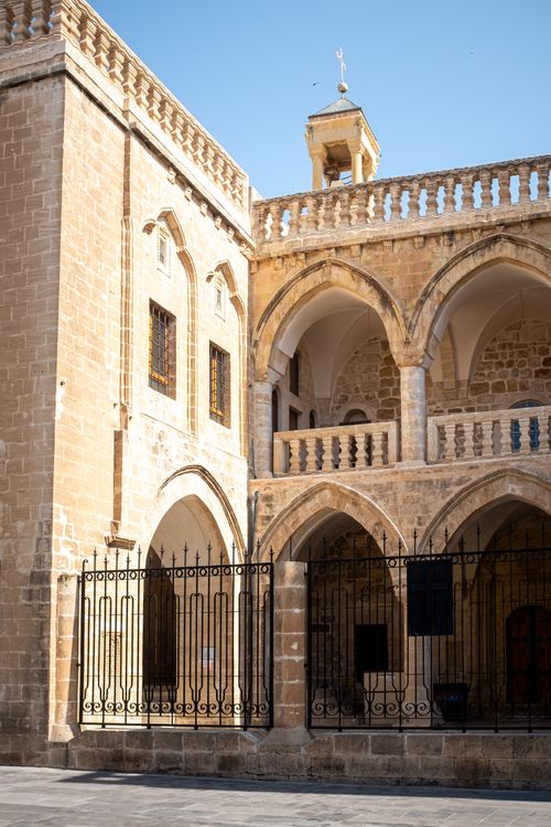 Free A historic building with arched architecture and stone facade under a clear blue sky. Stock Photo