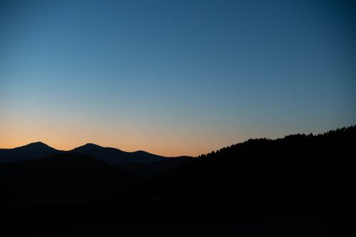 Free Silhouetted mountains at sunset create a serene and dramatic landscape scene. Stock Photo