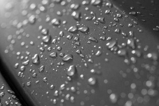 Detailed macro shot of water droplets on a metallic surface, showcasing texture and light.