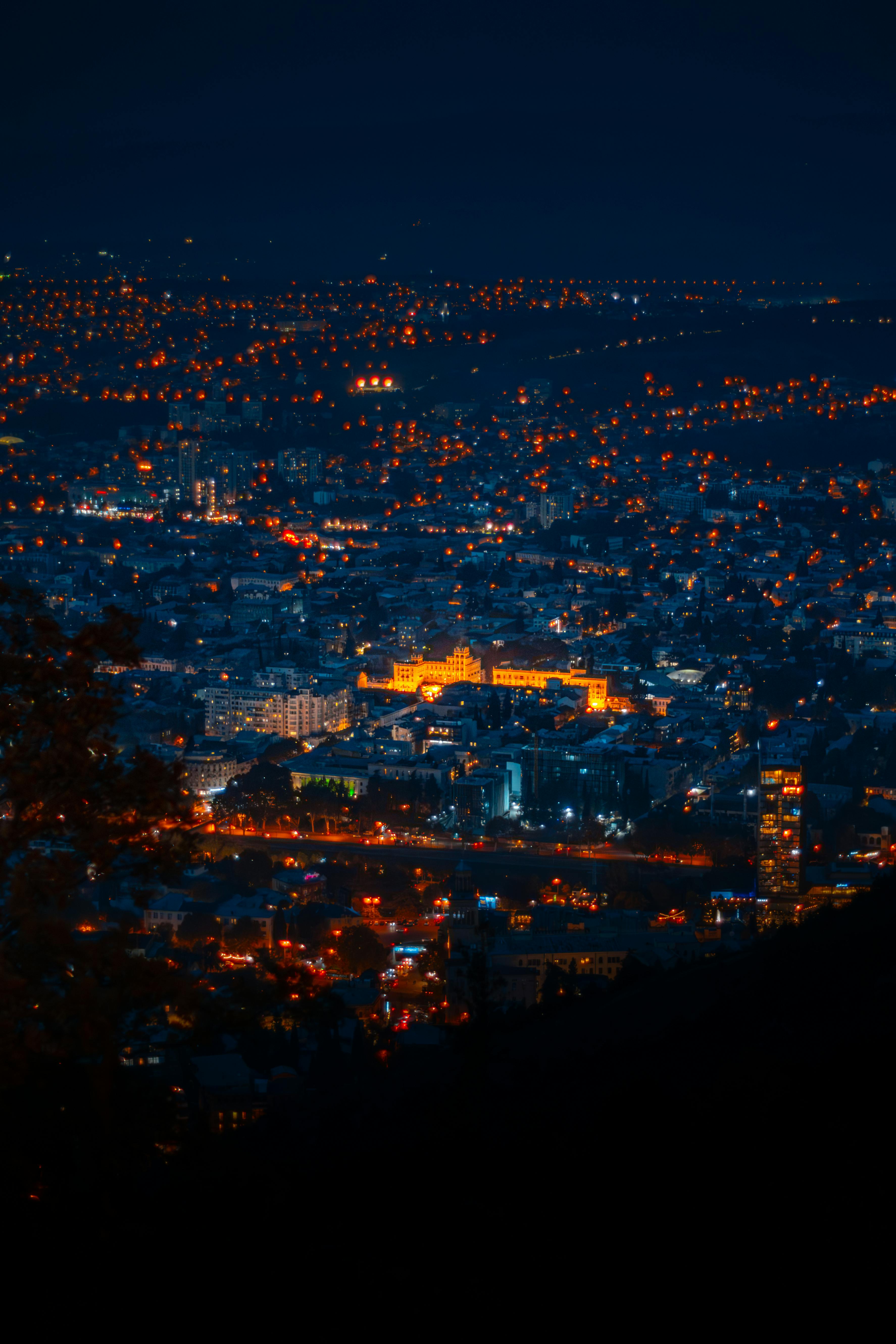 Stunning aerial night view of Tbilisi, Georgia, showcasing illuminated cityscape and vibrant lights.