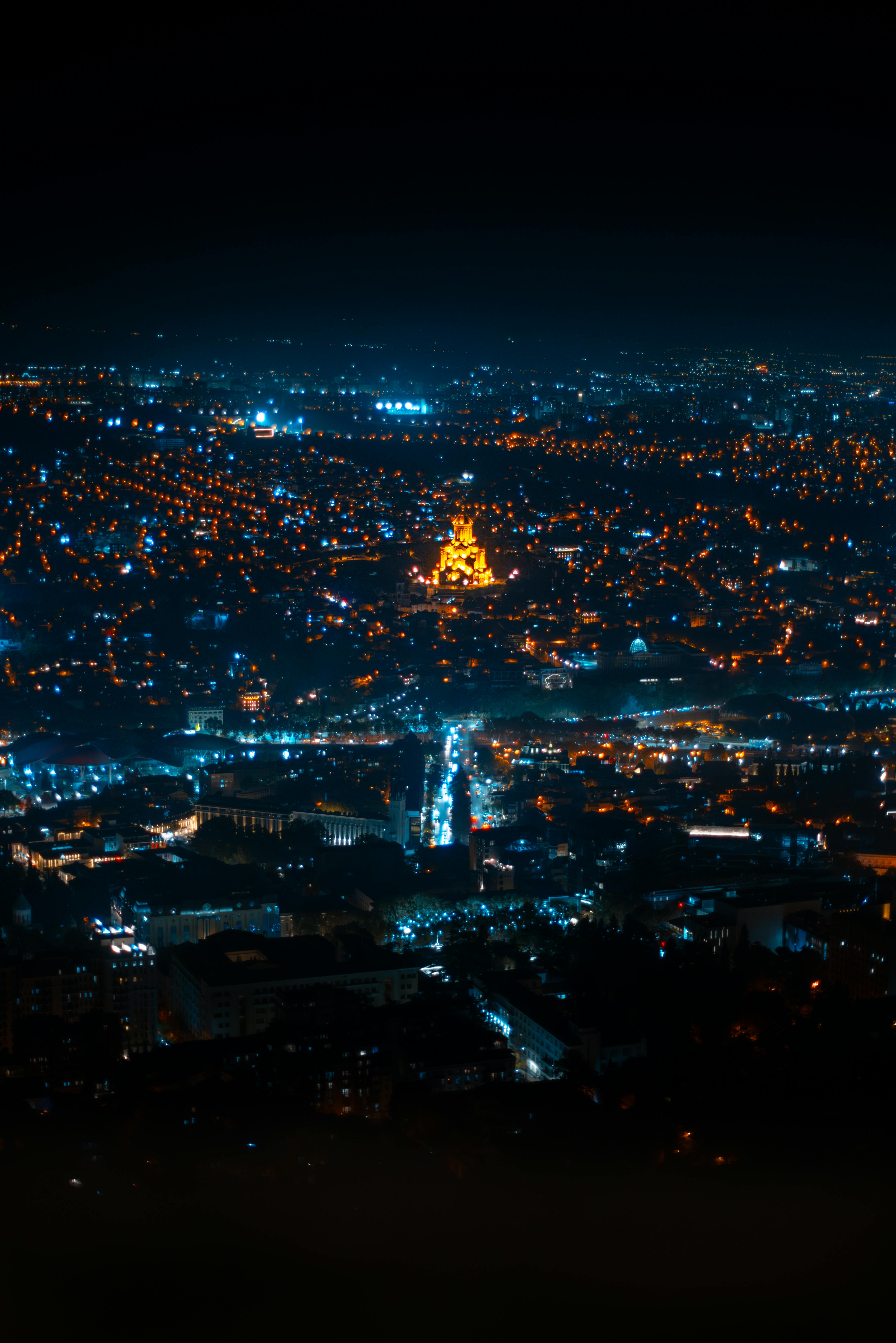 A breathtaking aerial night shot of Tbilisi, Georgia, showcasing its illuminated cityscape and glowing landmarks.