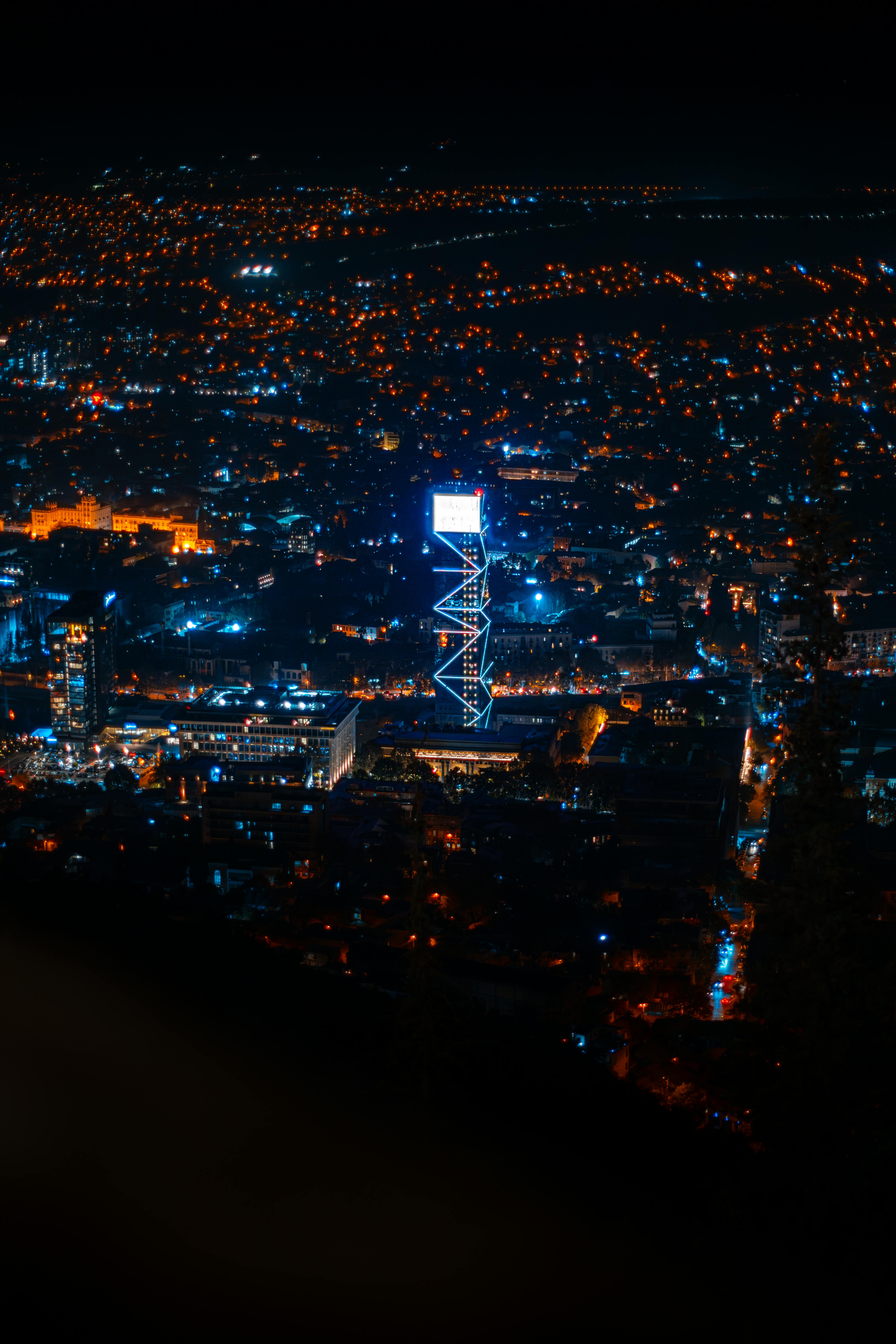 Explore the vibrant night skyline of Tbilisi, Georgia with its iconic illuminated landmarks.