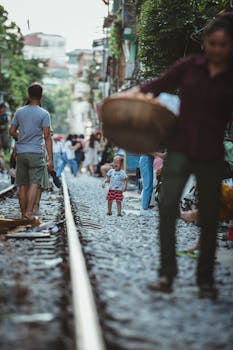 越南河内铁路轨道附近，行人与儿童在动态街景中穿梭