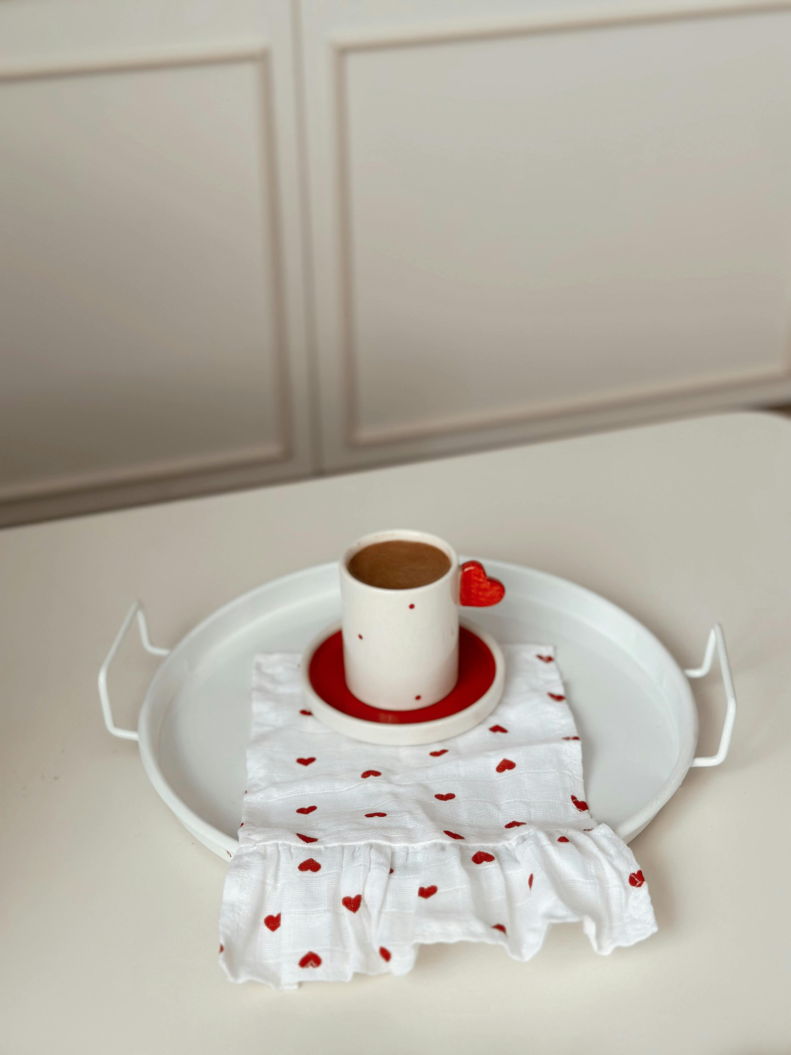 A romantic coffee cup with heart design on a tray, perfect for Valentine's Day.