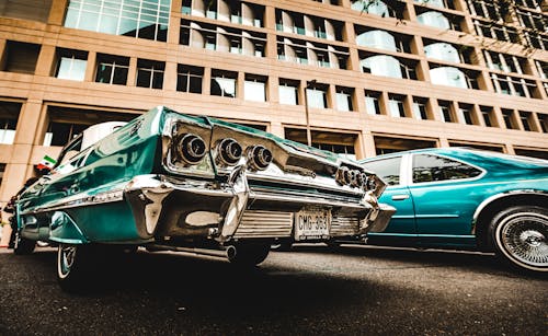 Green Vintage Car Parked Beside Brown Building