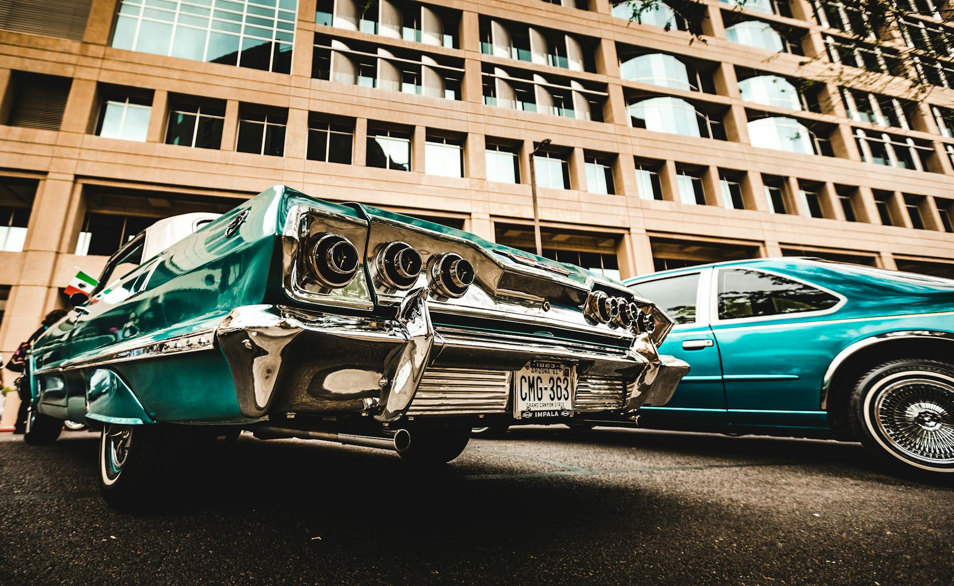 A classic vintage car parked on an urban street against a modern building backdrop.