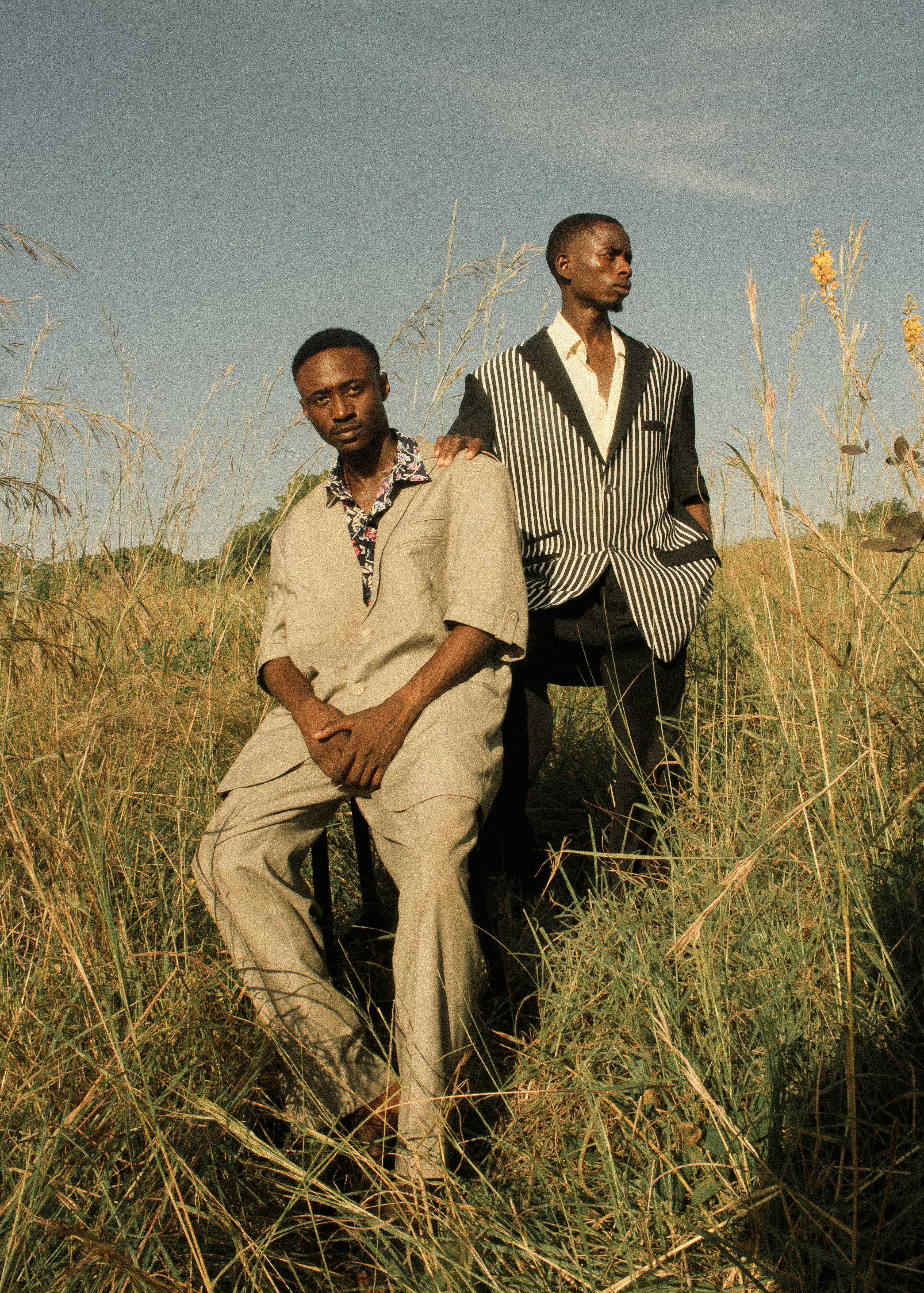 Zadarmo Dvaja štýloví muži sebavedomo pózujú na trávnatej lúke pod jasnou oblohou. Fotka z fotobanky