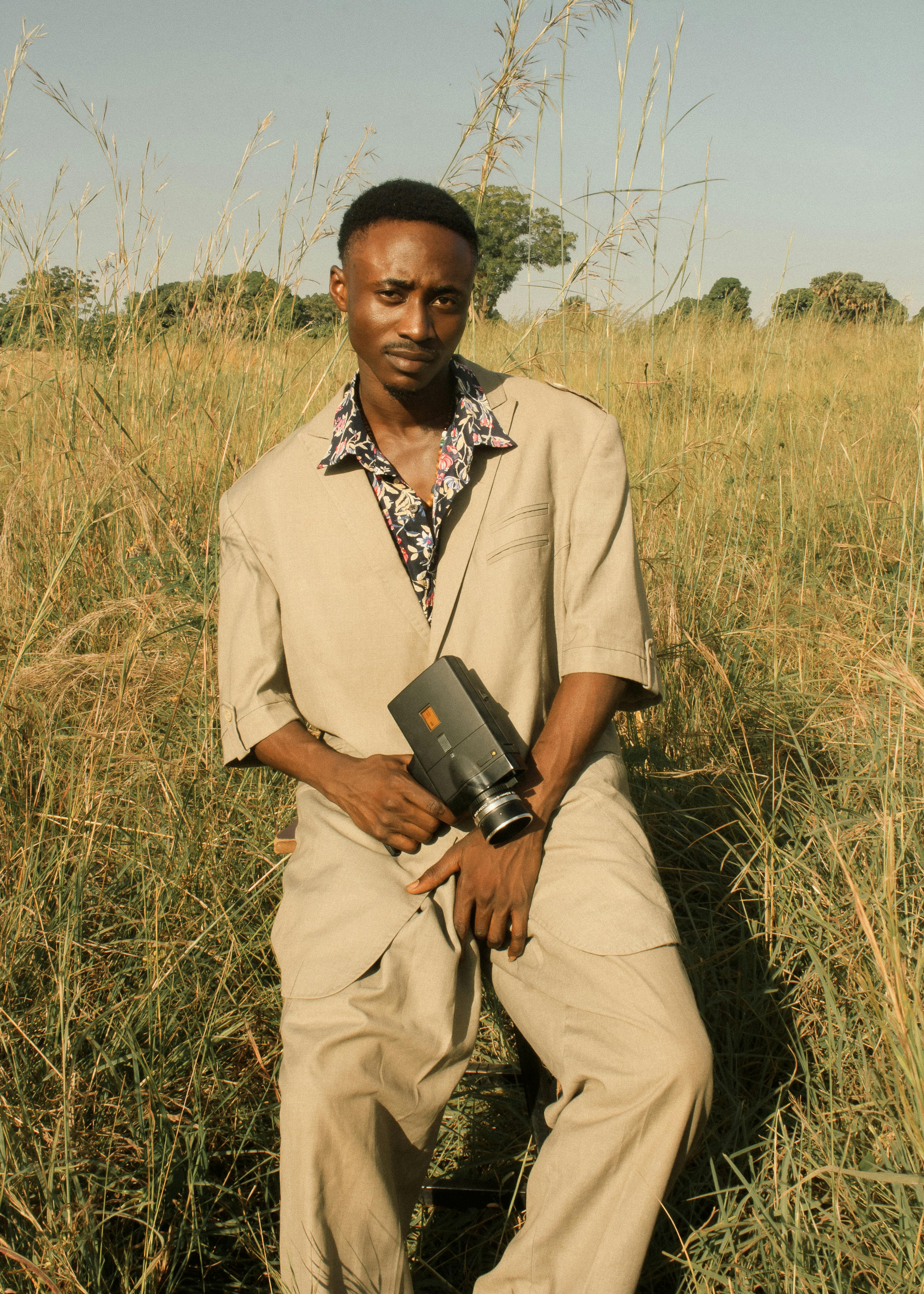 Portrait of an adult man in a field with a vintage camera, evoking a warm and nostalgic mood.