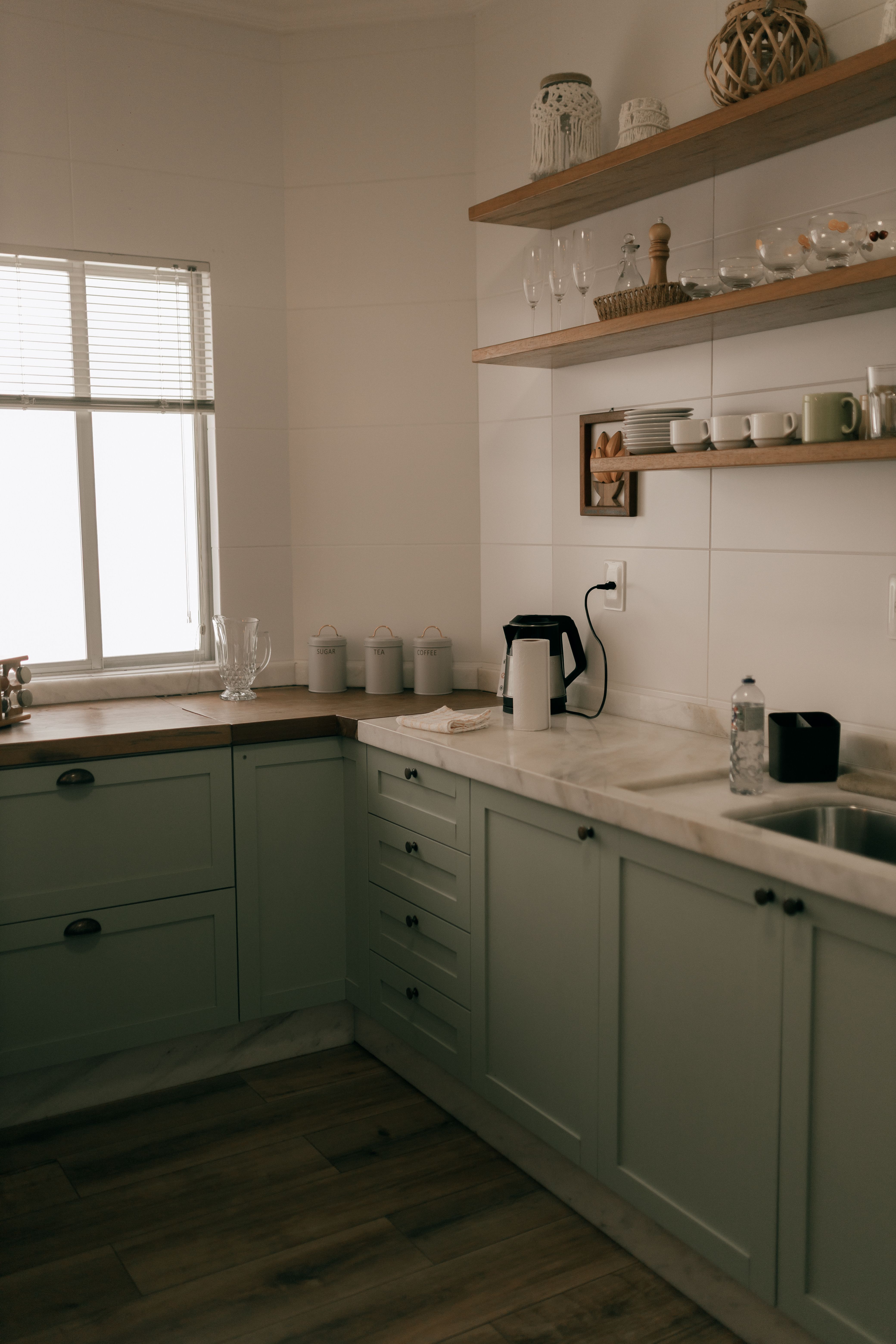 white under-cabinet shelves holding coffee mugs and spice jars for coffee syrups