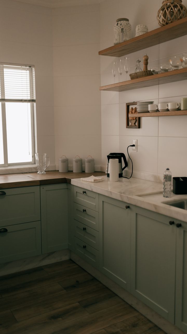 white under-cabinet shelves holding coffee mugs and spice jars for coffee syrups