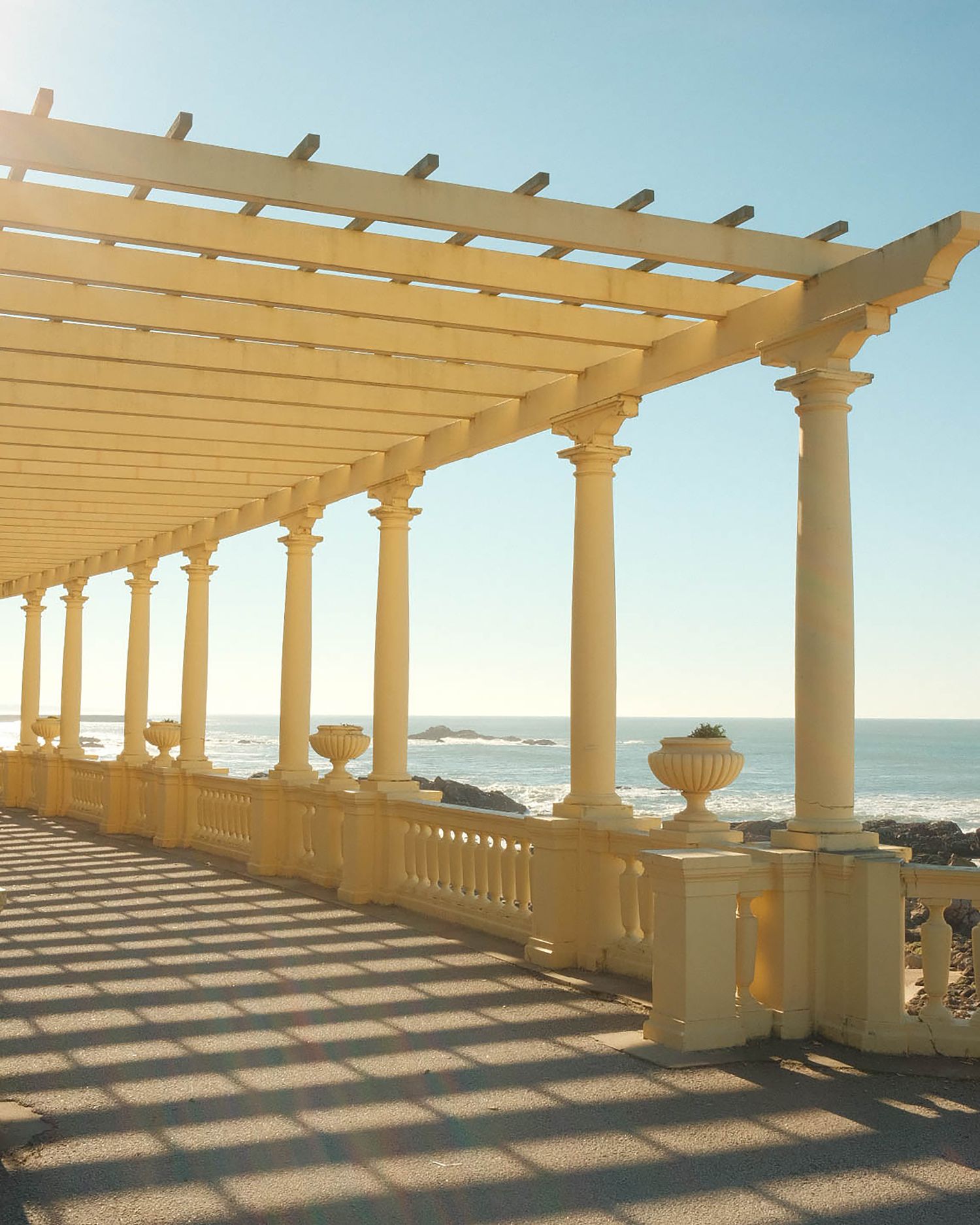 Pergola aménagée et ombragée le long d'une promenade ensoleillée, illustrant un espace extérieur convivial