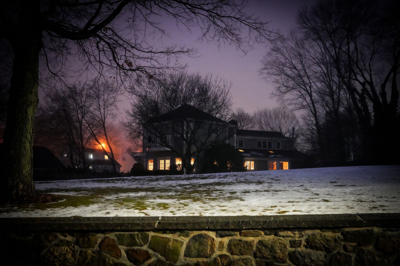 A cozy winter house at dusk with a snowy yard