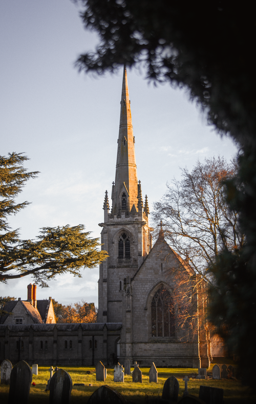 Free A gothic-style church tower in Shrewsbury, England, captured at sunset with surrounding trees. Stock Photo