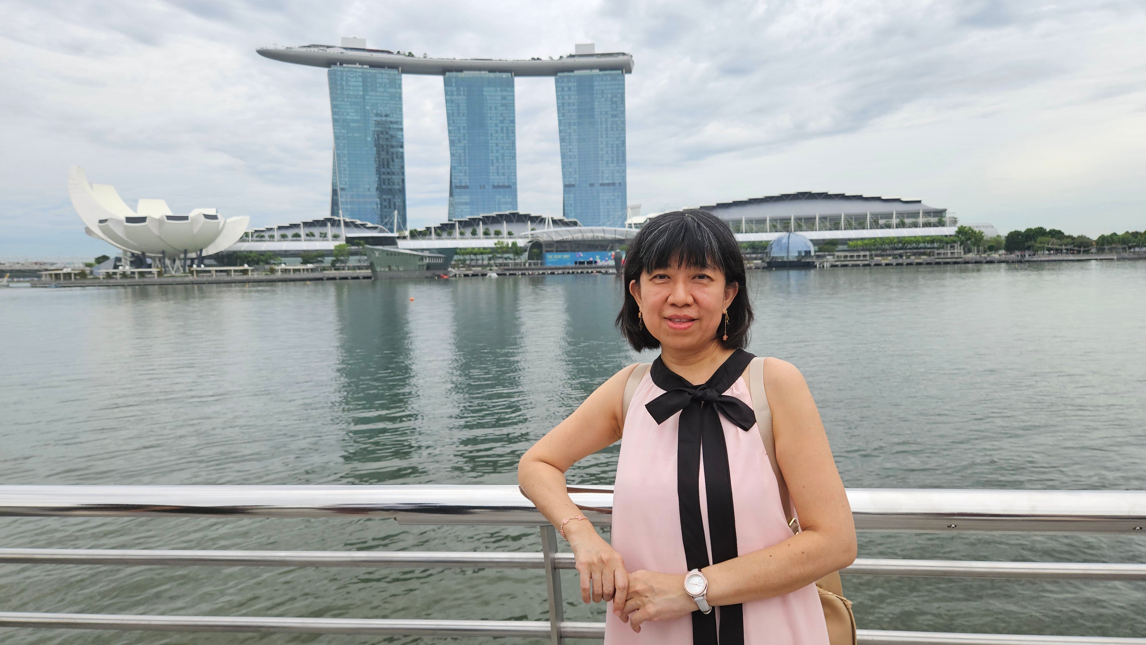 Woman posing by Marina Bay Sands with a cloudy sky in Singapore.