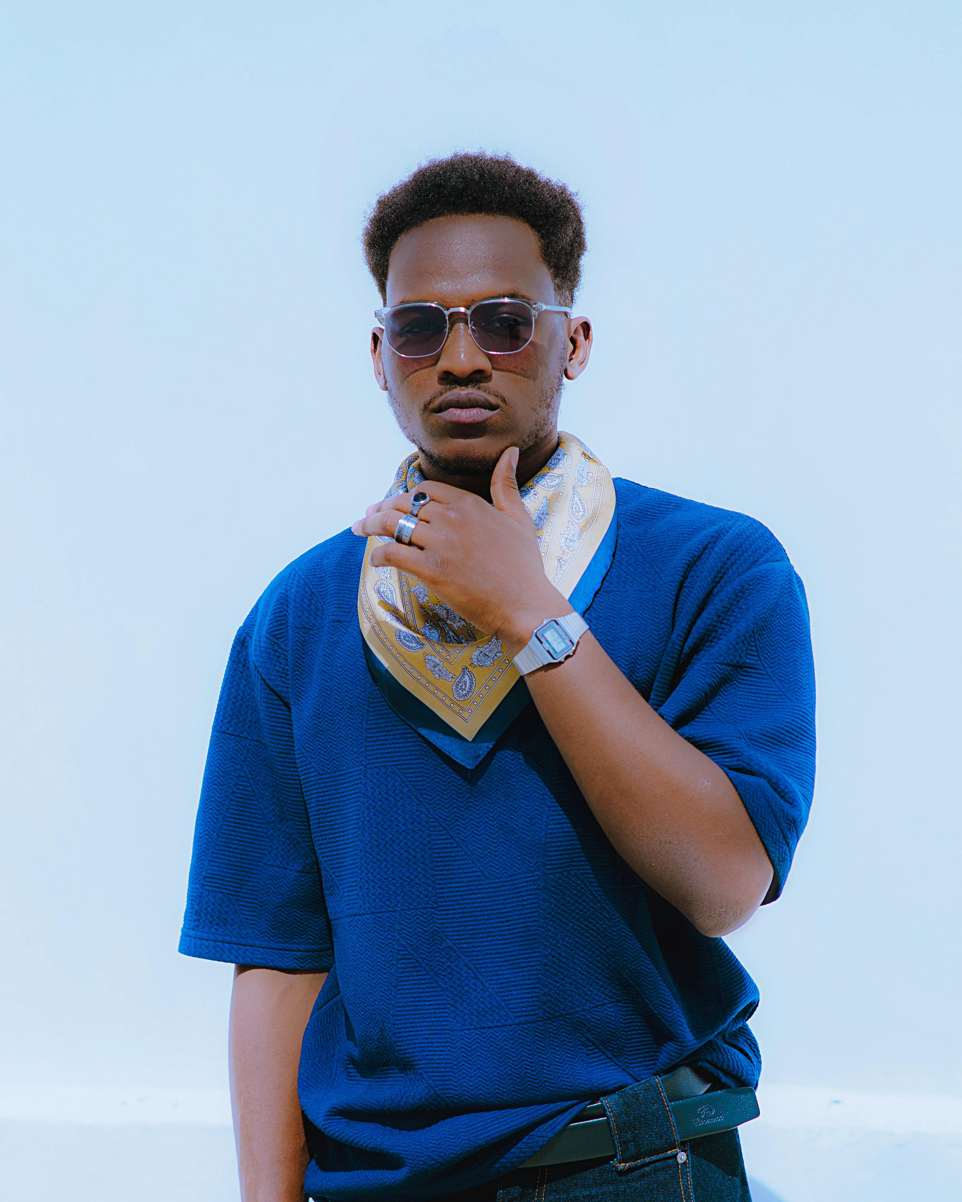 De franc Jove de moda en blau amb ulleres de sol i bufanda contra el cel clar Foto d'estoc