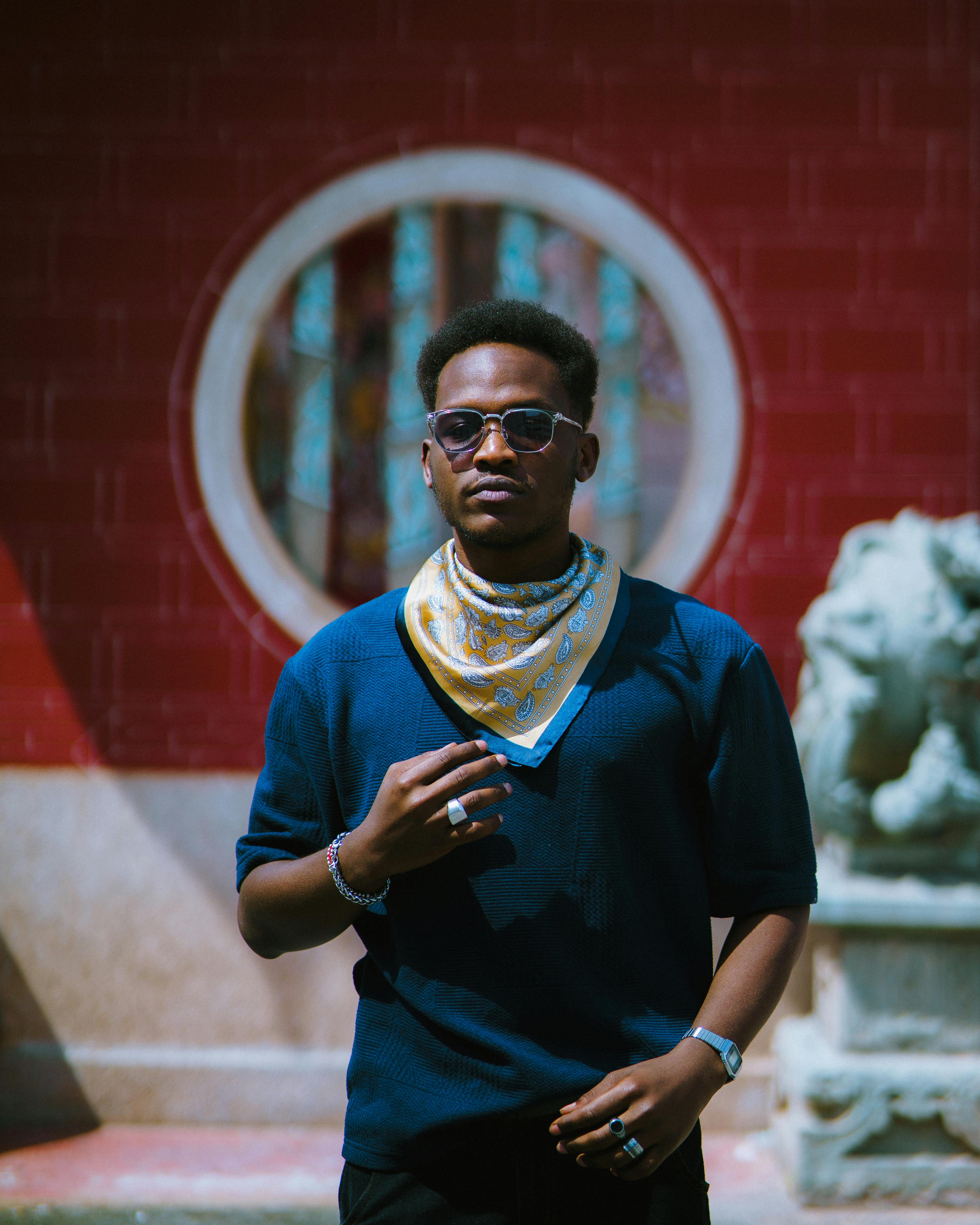 De franc Un home elegant amb ulleres de sol posa amb confiança sobre un fons de maó vermell. Foto d'estoc