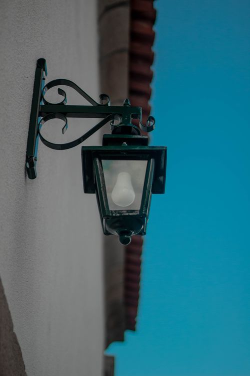 Free Elegant vintage outdoor lantern mounted on a wall with clear blue sky backdrop, offering classic charm. Stock Photo