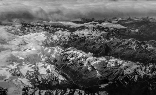 Free Stunning aerial view of snow-covered mountains beneath dramatic clouds. Stock Photo